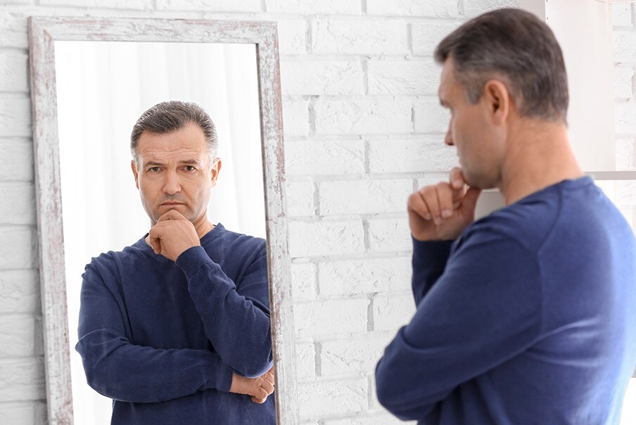 Uomo si guarda allo specchio pensieroso